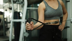 Close-up of a woman performing shoulder external rotation with a cable machine for strengthening muscles and improving shoulder stability during fitness training.